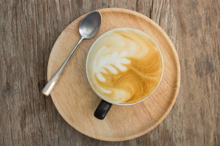 A Latte Coffee cup art on wooden desk.の写真素材