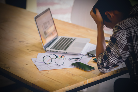stressed business man with graph document statistic and laptop on wood desk, vintage filterの写真素材