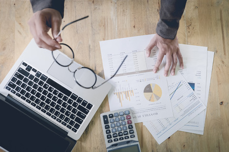 Business woman pointing at business document  with use laptop computer and  calculate in lastMonth. vintage effect. top view.の写真素材