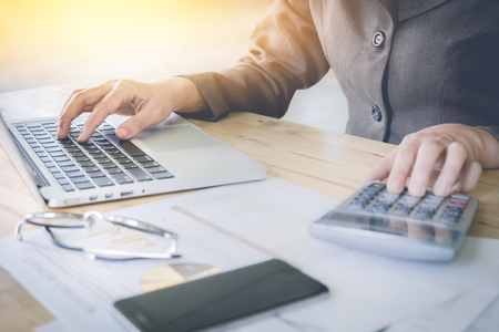Business woman using laptop computer and calculator  on wooden desk.の写真素材