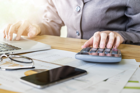 Business woman hand pointing calculator and using laptop computer for calculate stock maket chart of 
This month.の写真素材