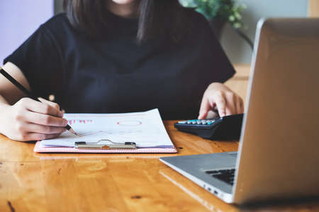 Business woman using document and using calculator to review balance sheet annual to calculating budget. for audit and Check integrity before investmentの写真素材