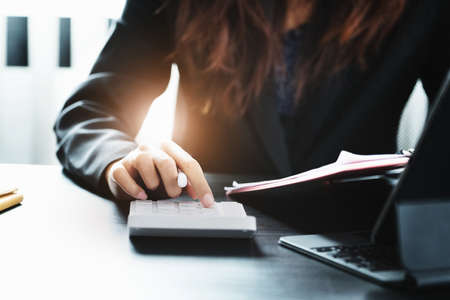 Business woman using calculator to review balance sheet annual using document and laptop computer to calculating budget. audit and Check integrity before investment conceptの写真素材