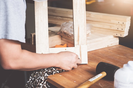 A carpenter measures the planks to assemble the parts, and build a wooden table for the customerの写真素材