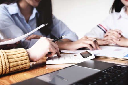 The auditor using calculator to calculate the budget document to investigate the misuse of company...