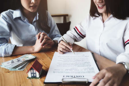 The customer holds a pen and reads the conditions in order to sign a house purchase contract with...