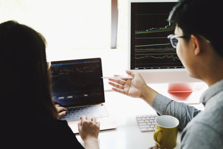 An investment expert points a pen at a computer monitor to analyze the stock market to teach you how...