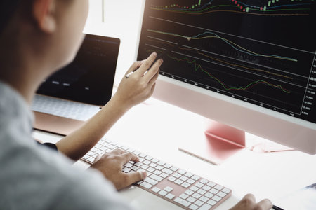 An investment expert points a pen at a tablet monitor to analyze the stock market to teach you how...