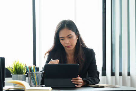 Business woman using tablet to review balance sheet annual using document to calculating budget. audit and Check integrity before investment concept.の写真素材