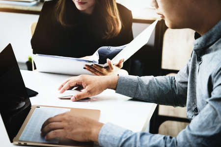Focus on the male business owner using a computer mouse, while woman is browsing through the...