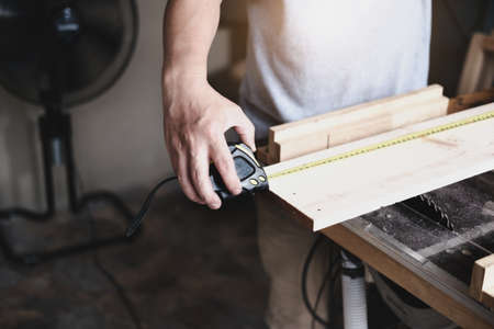 do-it-yourself concept Craftsmen use a tape measure to assemble wooden pieces to make wooden tables...