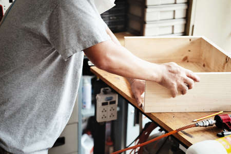 A carpenter measures the planks to assemble the parts, and build a wooden table for the customer.の写真素材