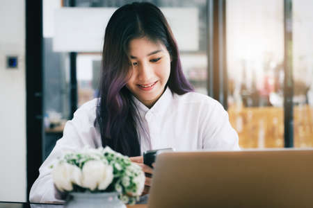 woman using mobile phone and computer to work in home office.の写真素材