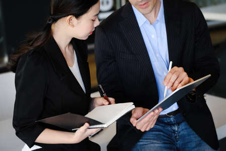 At the consultation, a male adviser uses a pen to point at a tablet to explain the profit...