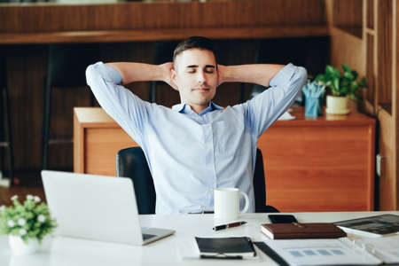 Male marketing manager resting and smiling while working to reduce drowsiness before using...