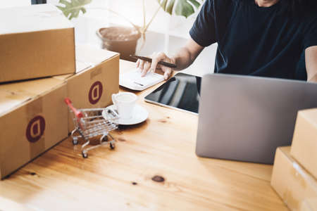 Work from home. happy women selling products online Start a small business owner by using a calculator and laptop computer to calculate prices and prepare for postage.の写真素材