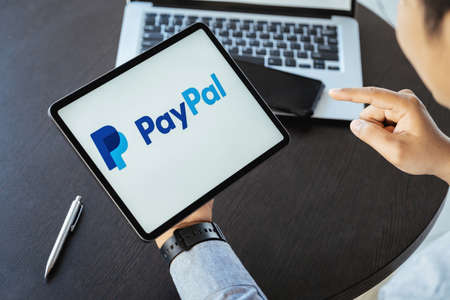 CHIANG MAI, THAILAND - NOV 28, 2021 : man hands holding ipad with PayPal apps on the screen. PayPal...