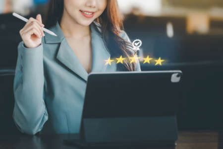 A female entrepreneur or businesswoman showing a smiling face while operating a computer tablet working on a wooden table.の写真素材