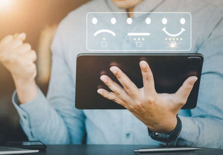 The concept of satisfaction rating, evaluation results, quality of work, male employees express their happiness after receiving a 5-star smiley face icon image from the company they work for.の写真素材