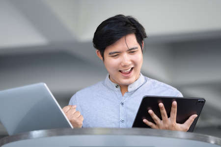 stock market profit analysis concept, risk management, financial freedom, male stock marketer using tablet, expressing joy in buying and selling shares for profit using internet media.の写真素材