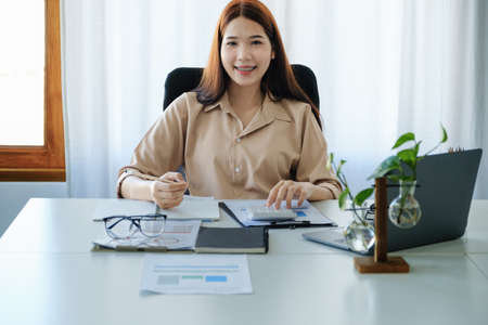 Young economists, accountants or financiers and investors are reviewing budget documents and using notebooks and calculators to study the impact and risk assessment of corporate investment management.の写真素材