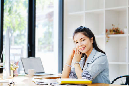An Asian entrepreneur or businesswoman shows a smiling face while working with using computer on a...