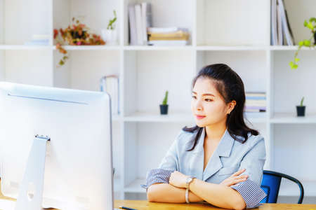 An Asian entrepreneur or businesswoman shows a smiling face while working with using computer on a...
