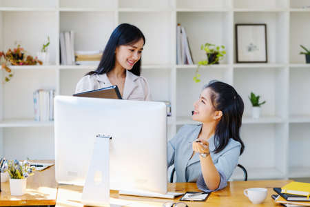 Consultation, discussion, marketing and investment concept, female employee pointing at computer monitor and colleague holding folder to draw conclusions and assess investment risks for the company.の写真素材