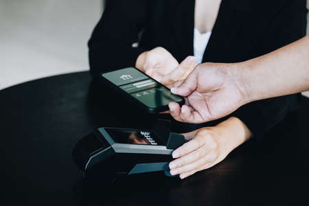 Payment security technology concept and service fees, Employees are holding electronic card machines for customers to use smartphone mobile to pay via paywave technology.の写真素材