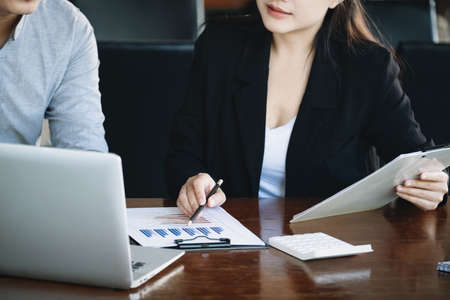 Teamwork concept, consultation, male economist holding pen pointing to budget, finance and investment documents, discussing and planning finances with female advisors in conference room.の写真素材