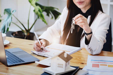 Asian woman accountant, business woman, real estate agent, holding a pen, pointing at home loan and...