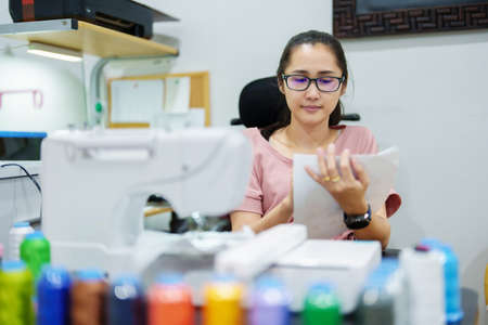 Embroidery, handicrafts, hobbies, SME business, family business, Portrait of Asian female designers are doing by designing patterns using automatic embroidery machines by customer order.の写真素材