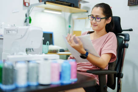 Embroidery, handicrafts, hobbies, SME business, family business, Portrait of Asian female designers are doing by designing patterns using automatic embroidery machines by customer order.の写真素材