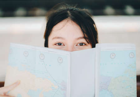 summer, relax, vacation, travel, portrait of a cute Asian girl looking at a map to plan a trip while...