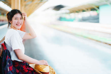 summer, relax, vacation, travel, portrait of cute Asian girl showing smile and showing joy while waiting at the train station for a summer tripの写真素材