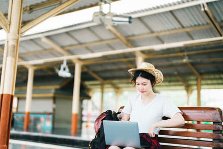 summer, relax, vacation, travel, portrait of beautiful Asian girl using the computer laptop at the train station while waiting for their travel timeの写真素材