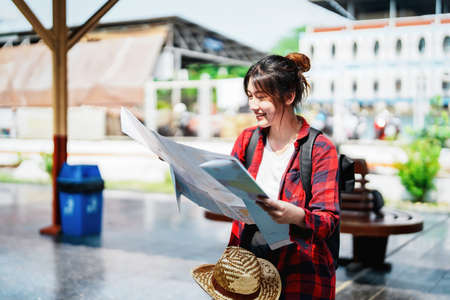 summer, relax, vacation, travel, portrait of a cute Asian girl looking at a map to plan a trip while...