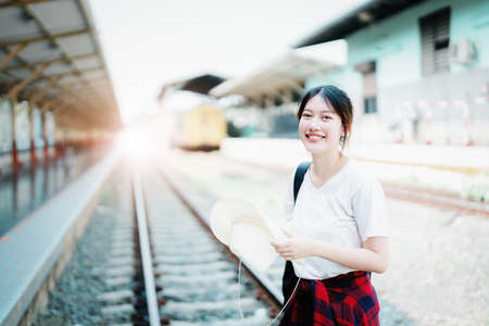 summer, relax, vacation, travel, portrait of cute Asian girl showing smile and showing joy while waiting at the train station for a summer tripの写真素材