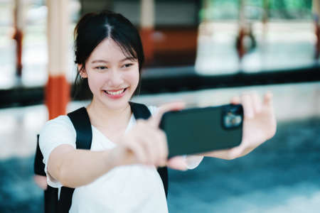 summer, relax, vacation, travel, portrait of beautiful Asian girl using the smartphone mobile take a photo selfie face yourself at the train station while waiting for their travel timeの写真素材