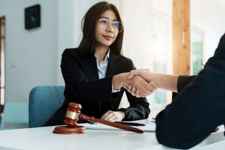 Law, consultation, agreement, contract, lawyer or attorney shakes hands to agree on the clients offer to be hired to fight the parties in courtの写真素材