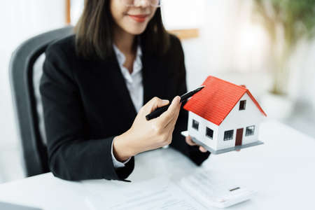 Law, agreement, contract, mortgage, woman holding a pen, pointing at a house to see the interest rate and asking for the limit to assess the risk before buying a house.の写真素材