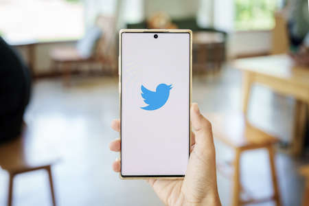 CHIANG MAI, THAILAND - May 13, 2022 :Women holding smartphone mobile with Twitter logo on the screen. Twitter is a social media online service for microblogging and networking communication.のeditorial素材