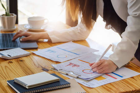 Young economists or accountants or financiers and investors are reviewing budget documents and using...