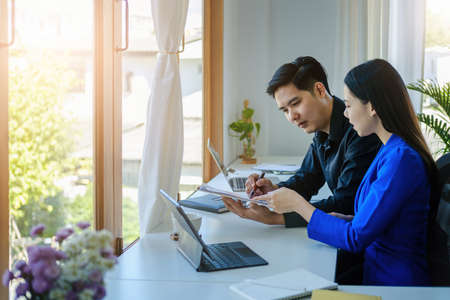 Teamwork concept, consultation, male economist holding pen pointing to budget, finance and investment documents, discussing and planning finances with female advisors in conference roomの写真素材