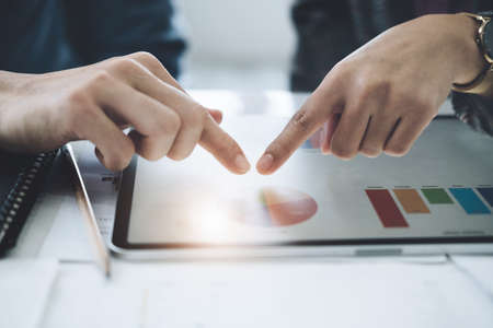 Negotiation, Analysis, Discussion, Asian young economist and marketer using tablet computer to plan investments and financial to prevent risks and losses for the company.の写真素材
