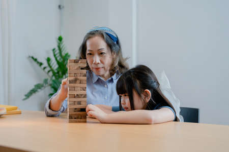 Asian portrait, grandchild granddaughter grandma grandmother and granddaughter happily join in activities to Block wood game Puzzle and enhance skills for grandchildren.の写真素材