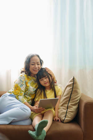 Asian portrait, Grandma and granddaughter doing recreational activities playing tablet computers on...
