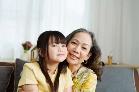 Asian portrait, grandma and granddaughter doing leisure activities and hugging to show their love and care for each other.の写真素材