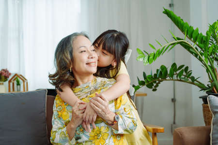 Asian portrait, grandma and granddaughter doing leisure activities and hugging to show their love and care for each other.の写真素材
