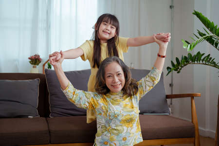 Asian portrait, grandma and granddaughter doing leisure activities and hugging to show their love and care for each other.の写真素材